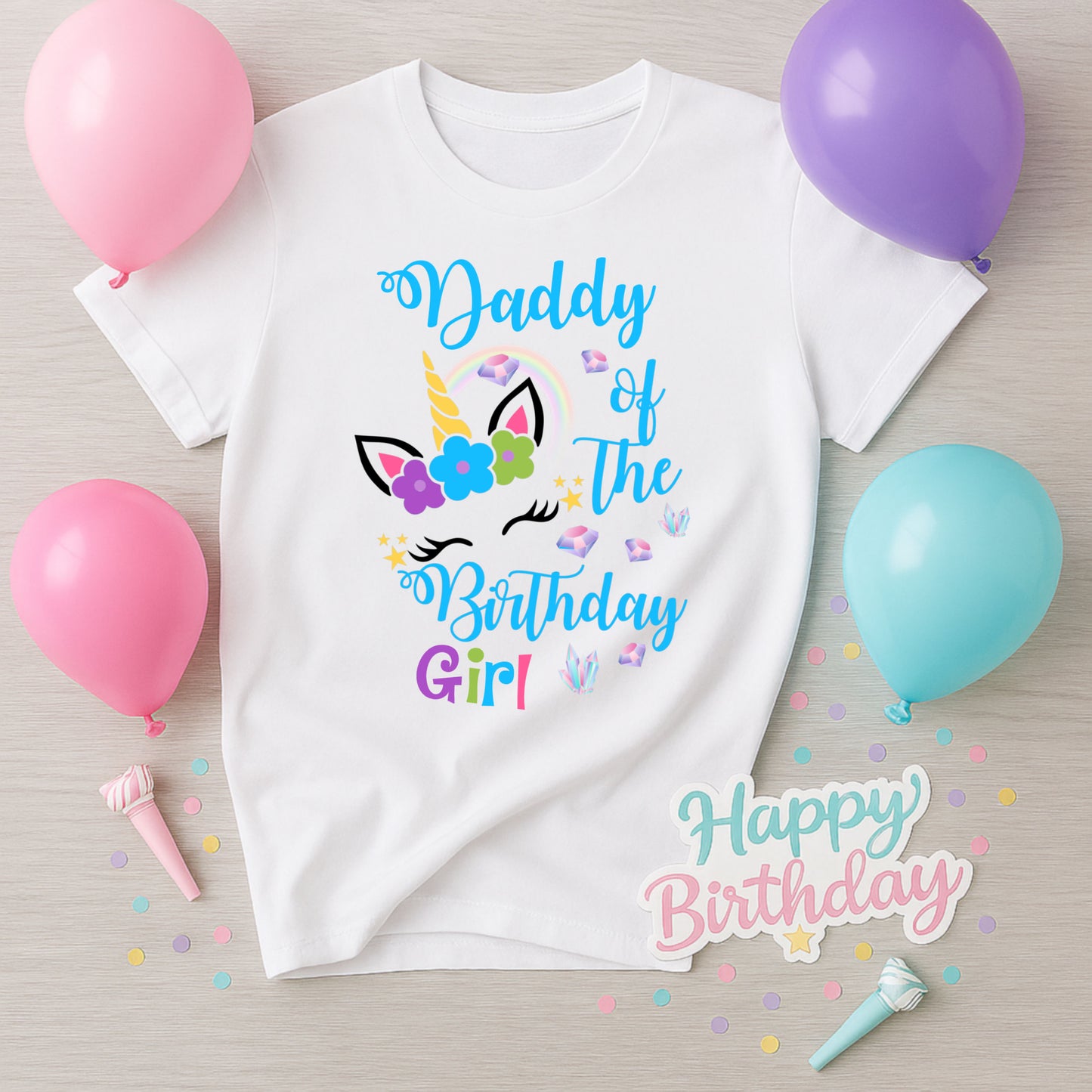 White t-shirt with 'Daddy of the Birthday Girl' text and unicorn design, surrounded by balloons and confetti on a wooden surface.